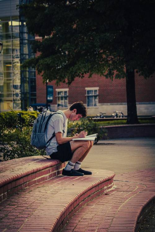 Student writing in notebook in Quad Area