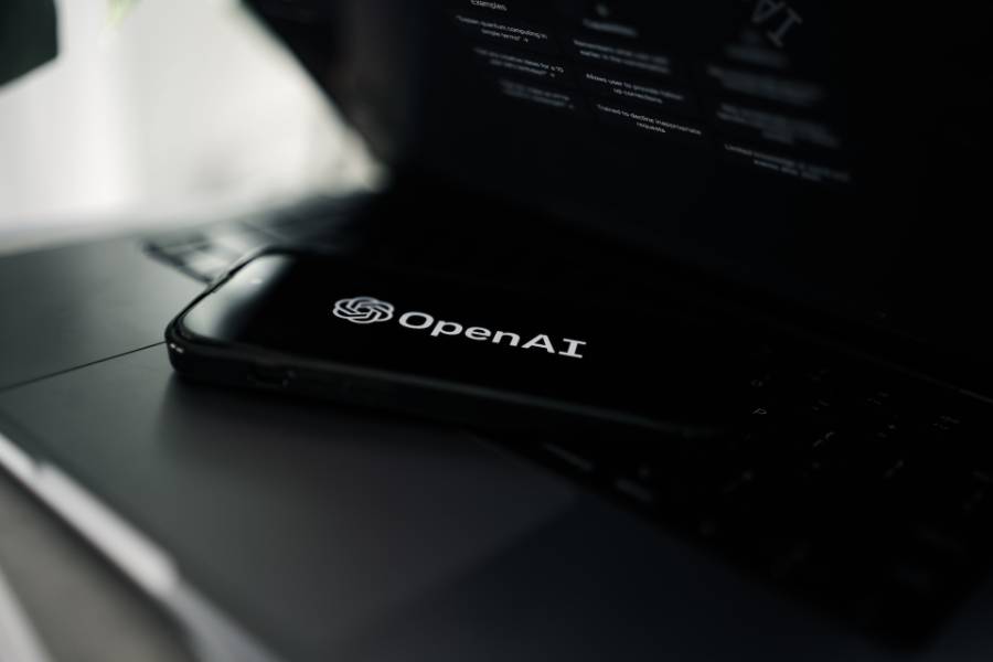 Phone on top of laptop with the words OpenAI